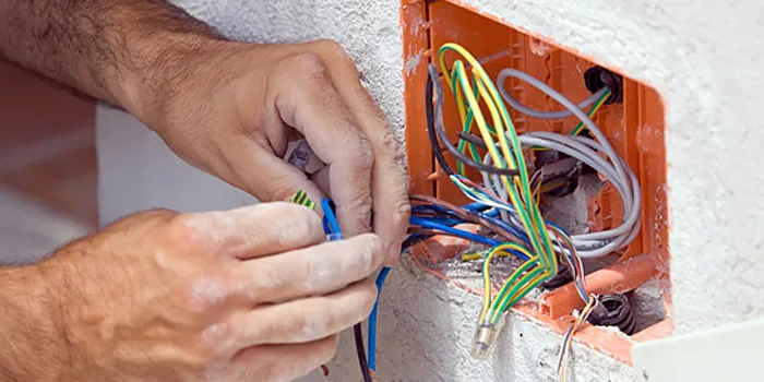 Elektriker verdrahtet Adern in einer Unterputzdose an einer Wand