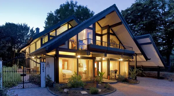 Modernes Fachwerkhaus am Abend mit beleuchteter Fassade und Vorplatz