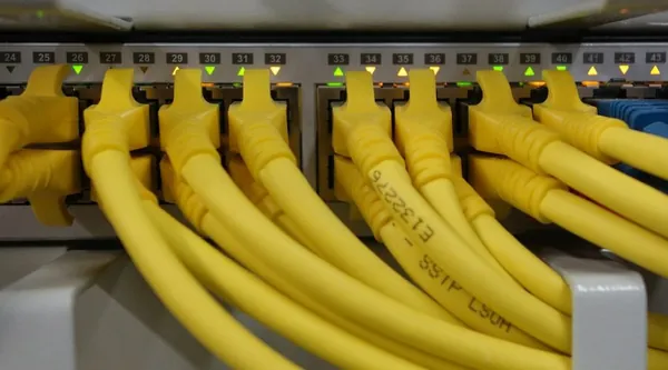 Gelbe Netzwerkkabel in einem Patchfeld mit nummerierten Ports