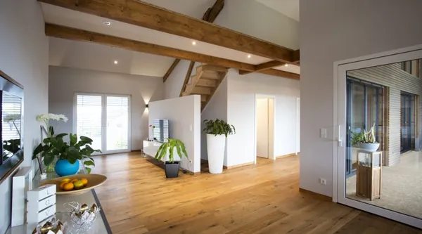 Offener Wohnraum mit Holzbalkendecke und eingebauten Deckenspots