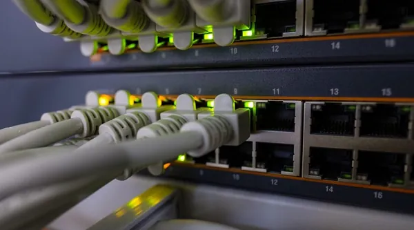 Patchkabel in einem Netzwerkverteiler mit leuchtenden Statusanzeigen