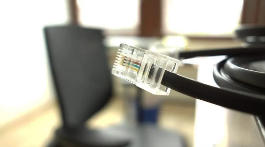 Netzwerkkabel mit RJ45-Stecker vor einem Schreibtisch
